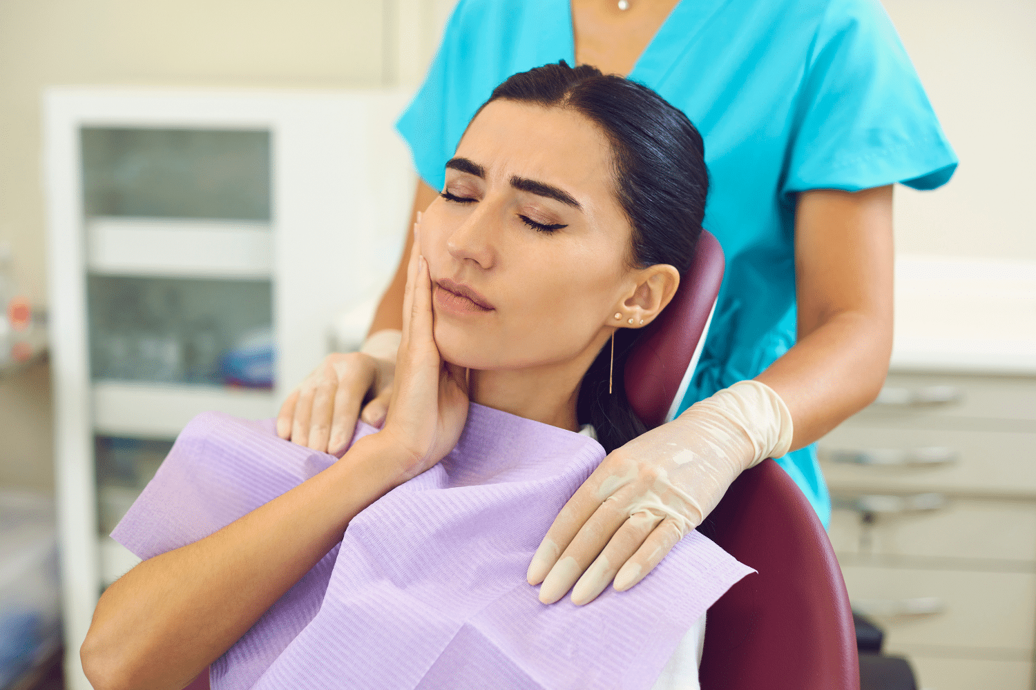 A Cary, NC woman sitting in the dentist office holding her face from tooth pain caused by a dental emergency