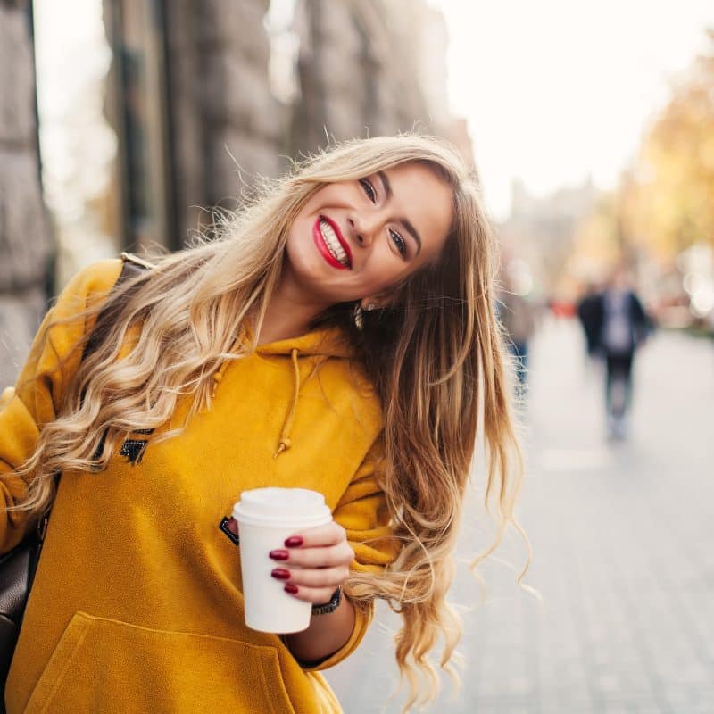 young woman in a yellow sweater smiling, showing off her white smile from Cary Family Dental