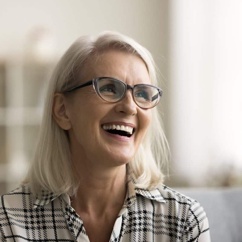 mature woman smiling on a couch, new dental implants