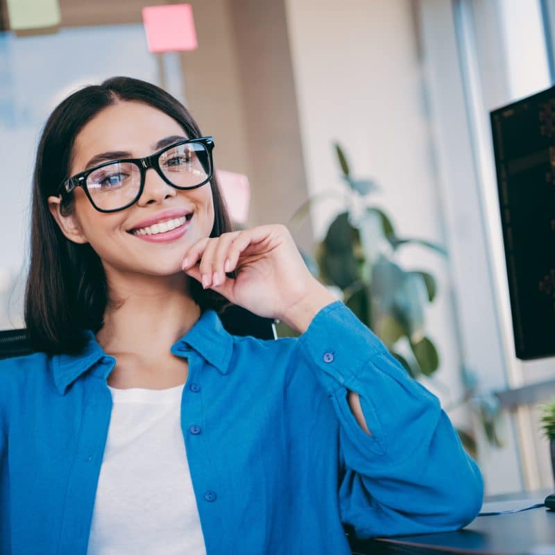 professional young woman sitting at her desk, perfect white teeth