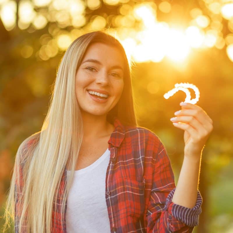 Woman holding invisalign braces outdoors, sunset