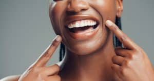 closeup, cropped smile of young woman pointing to her new dental crown