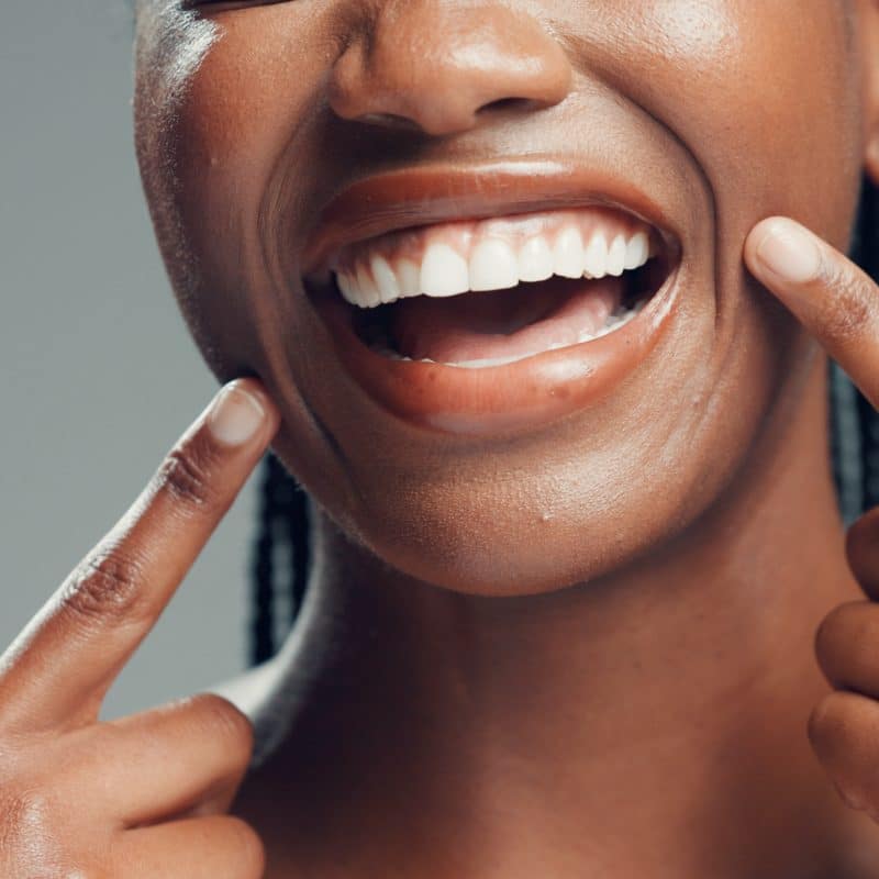 closeup, cropped smile of young woman pointing to her new dental crown